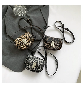 Flat lay of leopard print flap crossbody bags with square metal locks on a gray blazer background