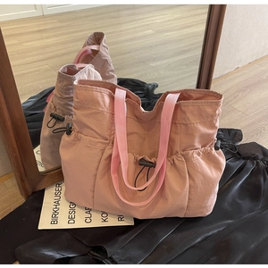 Detail of pink pleated tote bag showing multiple utility pockets and drawstring buckles
