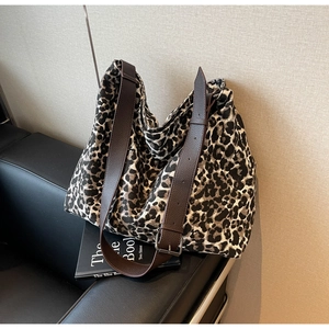 Detail of adjustable dark brown leather strap with silver buckle on leopard canvas tote bag