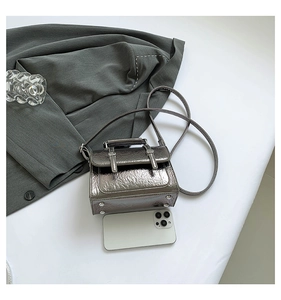 Detail view of mini silver messenger bag with crinkle texture and metal buckles