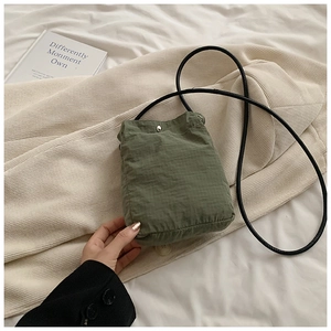 Detail of army green nylon mini crossbody bag with silver snap button and grid texture