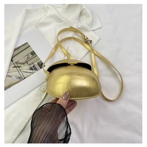 Detail of a mini golden dome-shaped crossbody bag with metallic texture and strap