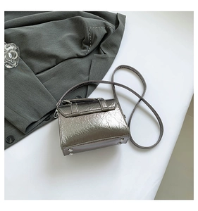 Close-up of metallic silver messenger bag with crinkle texture and metal feet detail