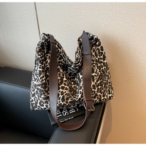 Detail of leopard print hobo tote bag featuring wide brown strap and metal buckle