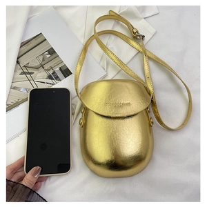 Detail of metallic gold mini crossbody bag with leather texture and engraved text detail
