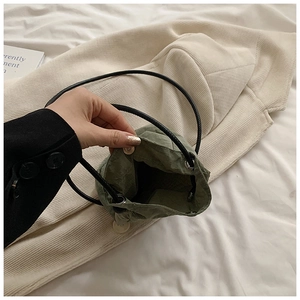Detail view of mini green nylon bucket bag with drawstring closure and magnetic clasp