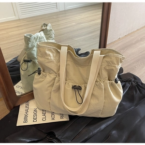 Detailed view of cream nylon tote bag with drawstring pocket and ruched texture details