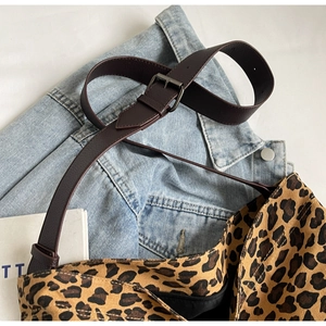 Detail of leopard print tote bag featuring brown leather strap and secure zip closure