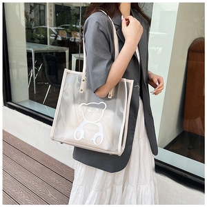 Fashionable transparent PVC beach tote bag with bear print shown on shoulder