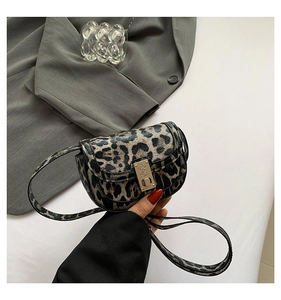 Close-up of leopard print saddle bag featuring golden metal buckle and textured pattern
