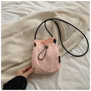 Detailed shot of pink drawstring mini crossbody bag with silver buckle and nylon texture