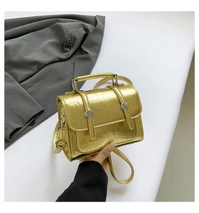 Detail of metallic gold cracked texture messenger bag with top handle and flap closure