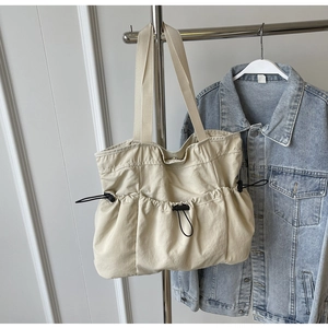 Detailed close-up of beige nylon tote bag with drawstring pleated design and wide straps