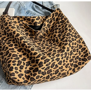 Detailed macro view of large leopard print canvas tote bag with brown shoulder strap and zipper
