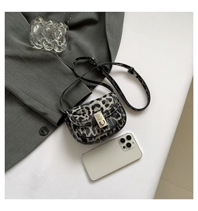 Detailed top view of leopard print mini bag with gold buckle next to a smartphone