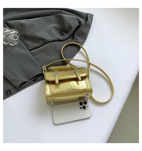 Detailed view of mini metallic gold pleated crossbody bag with a smartphone for size reference
