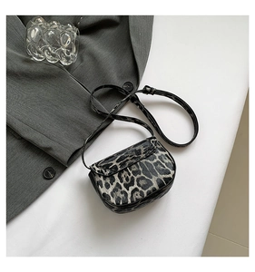 Close-up of stylish leopard print crossbody bag with mini flap and thin shoulder strap