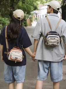 Outdoor couple wearing minimalist crossbody bags in orange and navy nylon with cord detail
