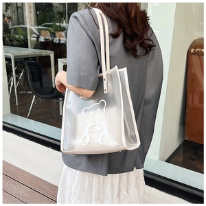 Detail of transparent PVC tote bag with white bear print and inner pouch in street setting