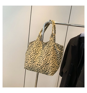 Detail of leopard print canvas tote bag hanging on display rack with black blazer