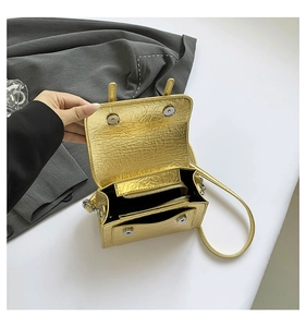 Detail view of gold metallic mini messenger bag showing dual magnetic closure and inner pocket