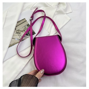 Detail of metallic rose red saddle bag with glossy texture and adjustable shoulder strap