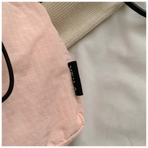 Detail of pink ripstop nylon mini bag featuring VEILA brand tag and black drawstring