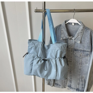 Detail of light blue pleated tote bag with three functional drawstring pockets