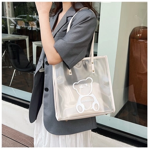 Detailed shot of transparent PVC tote bag with white bear pattern carried by a model