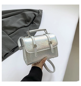 Detail of silver laser messenger bag with crinkle texture and metal buckle lock