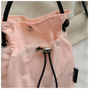 Detail of light pink mini drawstring bag with white grid pattern and nylon texture