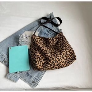Leopard print canvas tote bag with brown straps styled with a denim jacket and tablet