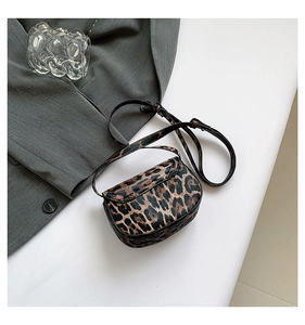 Detail of leopard print saddle bag with faux fur texture and slim black strap