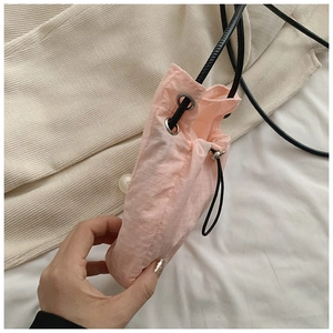 Close-up of pink nylon crossbody bag with drawstring closure and silver eyelets