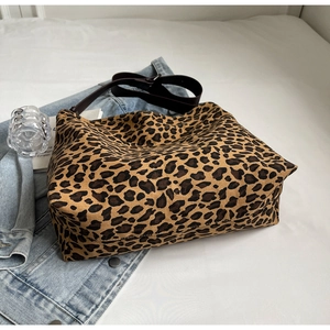 Macro view of leopard print canvas fabric with adjustable leather shoulder strap and buckle