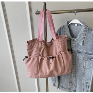 Pink pleated tote bag detail showing functional outer pockets with black drawstring toggles