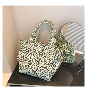 Detail showing the leopard print fabric texture and reinforced handles of this tote bag