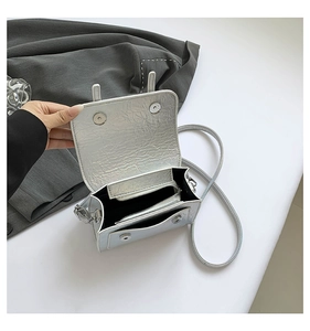 Detail view of silver metallic crossbody bag showing inner compartments and magnetic closure