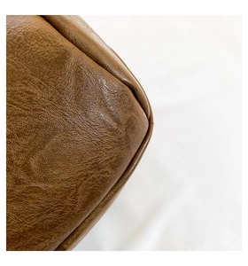 Makro-Detail einer braunen Ledertasche mit Vintage-Struktur und Paspelnaht am Rand
