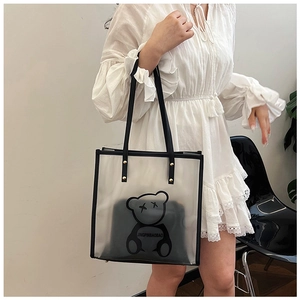 Detail view of transparent PVC tote bag with black cartoon bear and protective gold studs