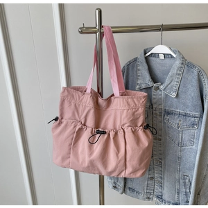 Pink nylon tote bag detail showing the adjustable drawstring outer pocket and durable strap