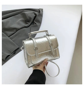 Close-up of silver crinkle textured messenger bag with metallic finish and top handle