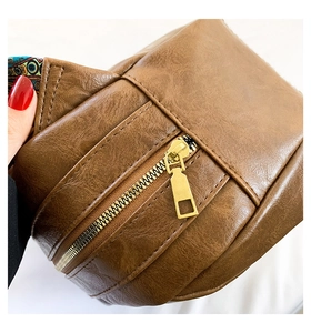 Detailaufnahme der braunen Muscheltasche mit goldenem Reißverschluss und Boho-Gurt