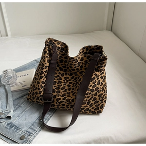 Detail of the leopard print canvas tote bag featuring brown leather straps and metal buckles