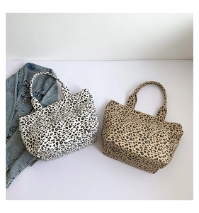 Detail view of leopard print tote bags in white and camel colors with canvas texture