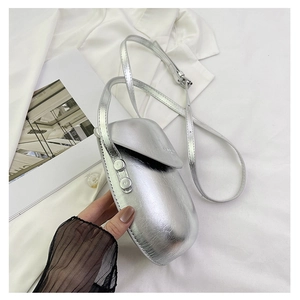 Detail view of the silver metallic egg-shaped crossbody bag on white silk background