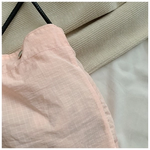 Detailed close-up of pink checkered nylon bag showing silver snap button and black strap