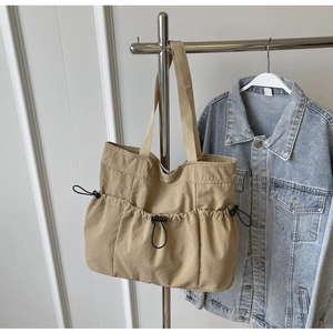 Detail view of khaki pleated tote bag featuring drawstring closure and textured canvas fabric