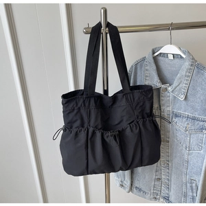 Detail of black drawstring tote bag made of water-resistant nylon with adjustable side pockets