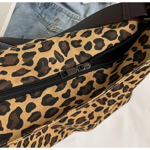 Close-up of leopard print canvas bag with dark brown leather strap and zip closure